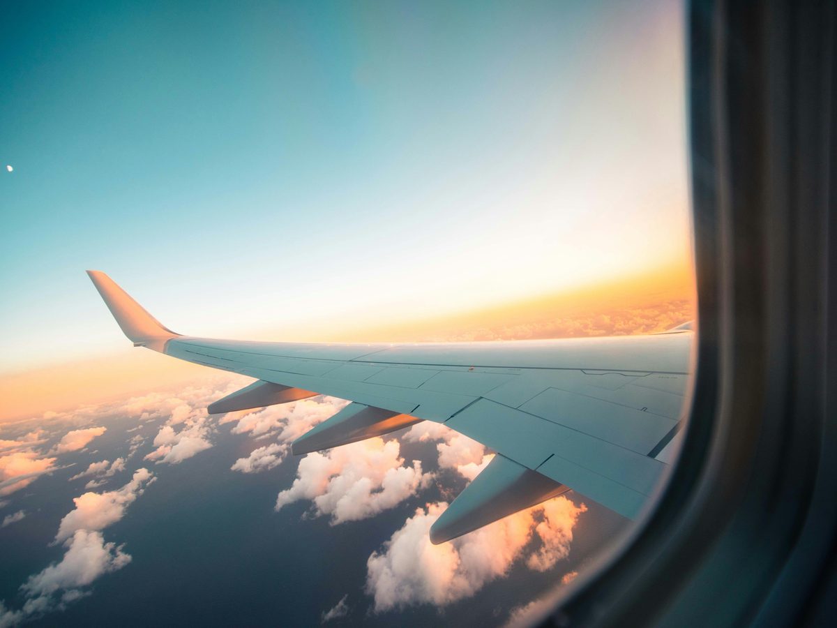 The wing of an airplane over clouds at sunset, seen from a window seat