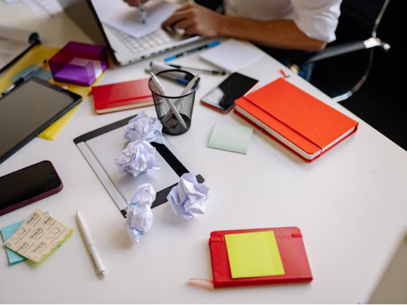 A home desk piled with papers, folders, and notes