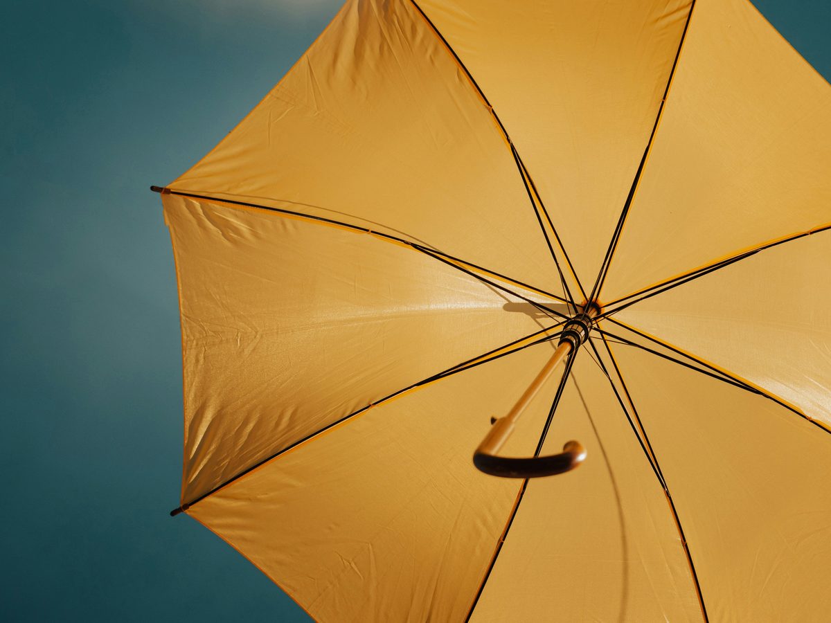 An open yellow umbrella against a clear blue sky